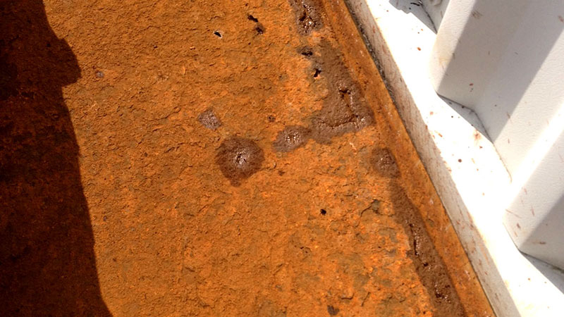 Rusting steel box gutter on electronics factory roof: standard roofing would entail removing roof panels and placing new gutter. CE Standards would have required complete shutdown of production.   Gallery Image
